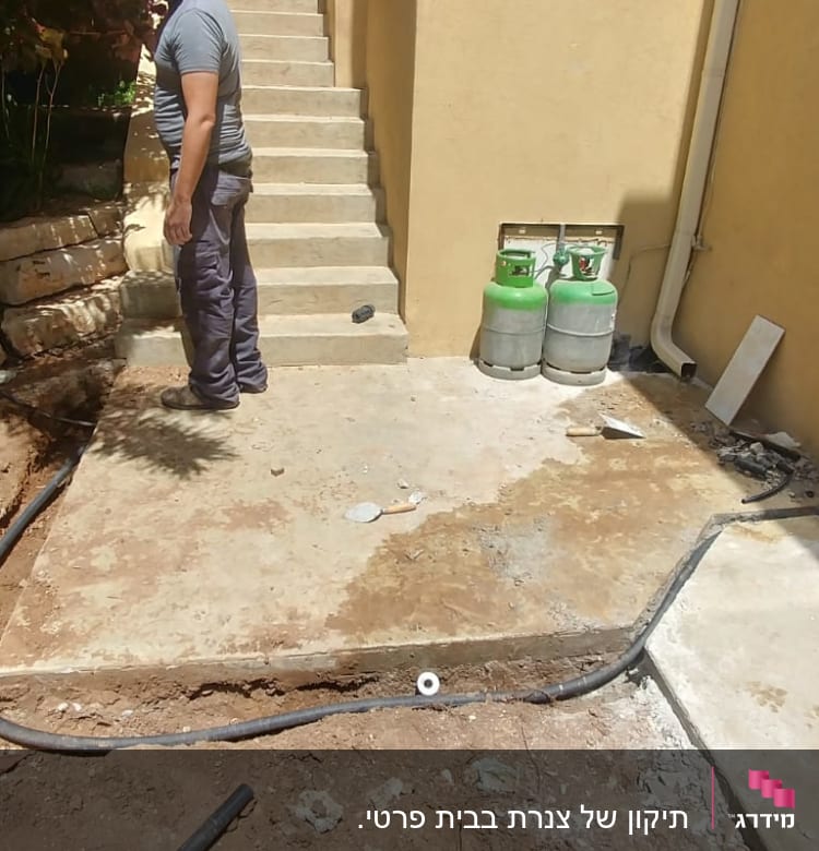 אדם עומד ליד צינור וכלי עבודה על הקרקע